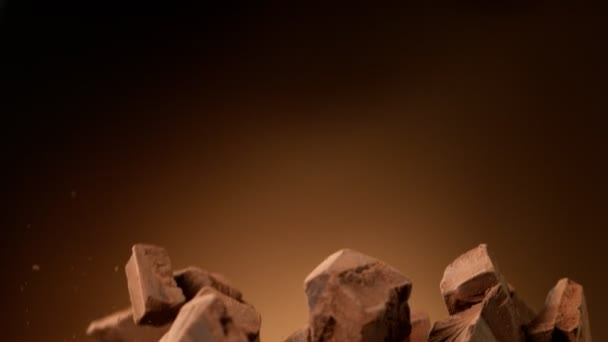 Mouvement super lent du groupe volant de morceaux de chocolat cru sur fond noir. Filmé sur caméra de cinéma à grande vitesse, 1000fps.