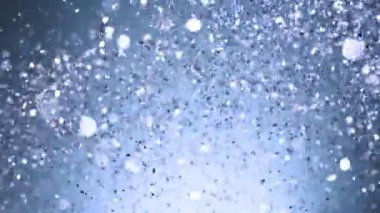 Siyah arka plan üzerine süper ışıltılı, yavaş gümüş parçacıkları. Odak sığ derinliği. Yüksek hız sinema kamerası, 1000 fps üzerinde filme.