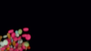 Siyah arka planda karışık hapların düşüşü çok yavaş. Yüksek hızlı sinema, yavaş çekim kamera, 1000fps.