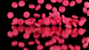 Siyah arka planda pembe hapların düşüşü çok yavaş. Yüksek hızlı sinema, yavaş çekim kamera, 1000fps.