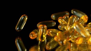 Siyah arka planda düşen altın hapların süper yavaş çekimi. Yüksek hızlı sinema, yavaş çekim kamera, 1000fps.