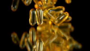 Siyah arka planda düşen altın hapların süper yavaş çekimi. Yüksek hızlı sinema, yavaş çekim kamera, 1000fps.