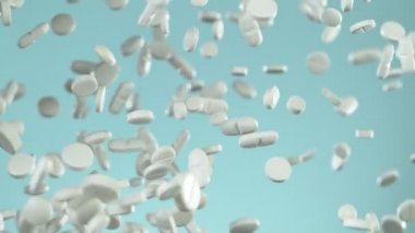 Mavi arka planda beyaz hapların düşüşü çok yavaş oluyor. Yüksek hızlı sinema, yavaş çekim kamera, 1000fps.