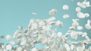 Mavi arka planda beyaz hapların düşüşü çok yavaş oluyor. Yüksek hızlı sinema, yavaş çekim kamera, 1000fps.