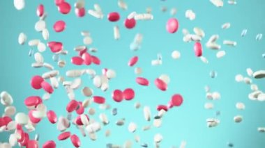 Mavi arka planda karışık hapların düşüşü çok yavaş. Yüksek hızlı sinema, yavaş çekim kamera, 1000fps.