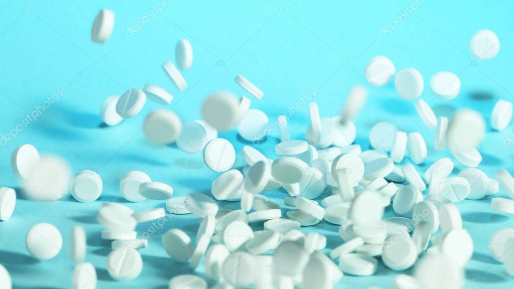 Freeze motion of flying pills on blue background