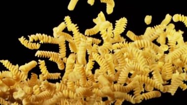 Süper yavaş çekimde pişmemiş İtalyan makarnası, siyah arka planda. Yüksek hızlı sinema kamerası, 1000 fps..