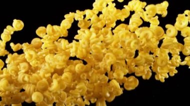 Süper yavaş çekimde pişmemiş İtalyan makarnası, siyah arka planda. Yüksek hızlı sinema kamerası, 1000 fps..