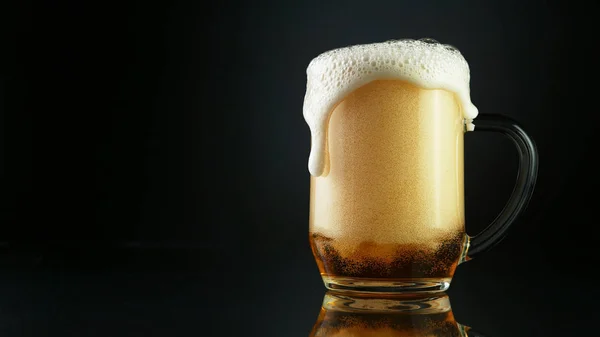 黒の背景に隔離されたガラスのパイントから溢れるビール泡 — ストック写真