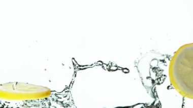 Limon dilimlerinin beyaza su sıçratarak çok yavaş hareket etmesi. Yüksek hızlı sinema kamerası, 1000 fps..