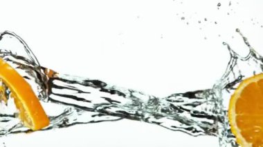 Beyaz zemin üzerinde su sıçraması olan portakal dilimlerinin süper yavaş çekimi. Yüksek hızlı sinema kamerası, 1000 fps..