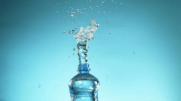 Exploding fresh water from plastic bottle on soft blue background. Free space for text
