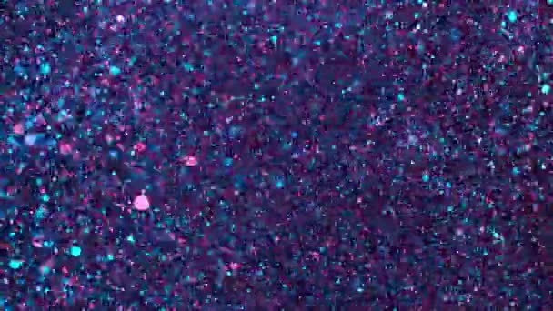 Mouvement super lent de particules colorées scintillantes sur fond noir. Faible profondeur de mise au point. Filmé sur caméra de cinéma à grande vitesse, 1000 images par seconde.