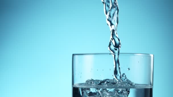 Super Slow Motion Pouring Water Glass Blue Background Filmed High — Stock Video