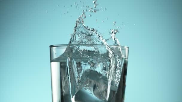 Super Zeitlupe Fallender Eiswürfel Ein Glas Wasser Auf Blauem Hintergrund — Stockvideo