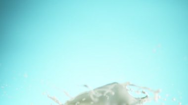 Yumuşak mavi arka planda izole edilmiş süper yavaş süt sıçraması. Yüksek hızlı sinema kamerası, 1000 fps..