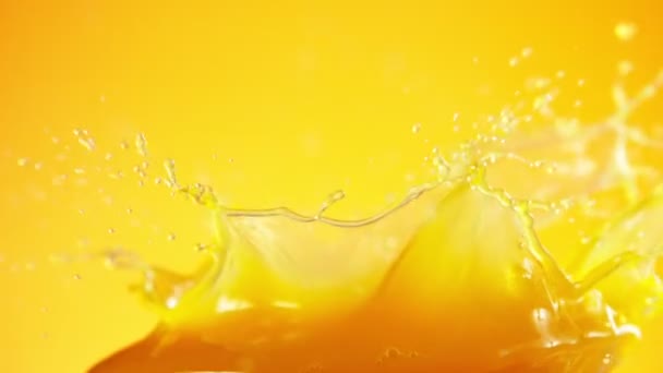 Mouvement super lent des éclaboussures de jus d'orange isolées sur fond coloré. Filmé sur caméra de cinéma à grande vitesse, 1000 images par seconde .
