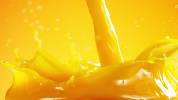 Mouvement super lent de verser du jus d'orange isolé sur fond coloré. Filmé sur caméra de cinéma à grande vitesse, 1000 images par seconde .