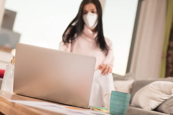 Young woman in home quarantine, wearing face mask protection. New virus covid-19. Home office and working from home.