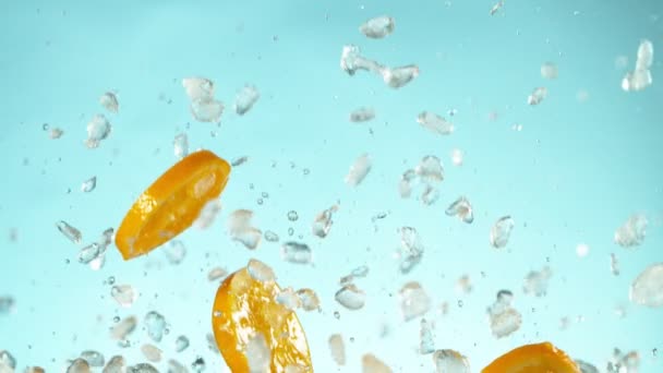 Super Zeitlupe Fallender Orangenscheiben Mit Crushed Ice Auf Blauem Hintergrund — Stockvideo