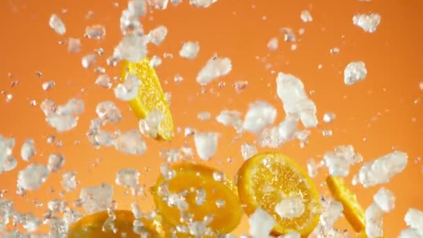 青の背景に砕いた氷でオレンジのスライスを落下の超遅い動き 高速フィルムカメラで撮影しました — ストック動画