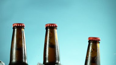 Mavi arka planda buzla birlikte düşen bira şişelerinin süper yavaş çekimleri. Yüksek hızlı sinema kamerası, 1000 fps..