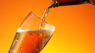 Altın arka planda şişeden cama bira dökmek. Ayrıntılı olarak makro çekim