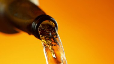 Altın arka planda şişeden bira dökmek. Ayrıntılı olarak makro çekim