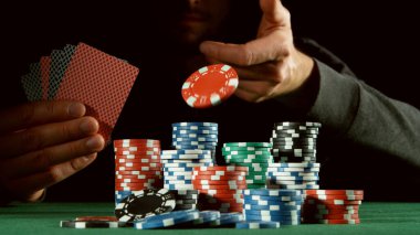 Poker oyuncusu kırmızı çip atıyor. Risk oyunları, poker fişleri.