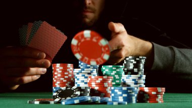 Poker oyuncusu kırmızı çip atıyor. Risk oyunları, poker fişleri.