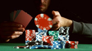 Poker oyuncusu kırmızı çip atıyor. Risk oyunları, poker fişleri.