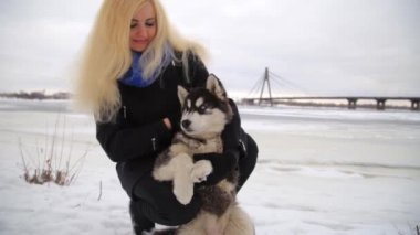 Siberian dış yapraklar malamute köpekler dışında ile oynayan sarışın kızla kış manzarası.
