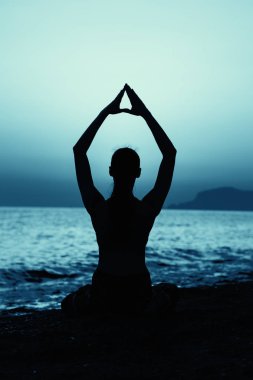 Gün batımında Yoga fitness egzersiz sahilde pratik genç sağlıklı kadın.