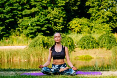 Yeşil park Yoga egzersiz yaparak genç kadın. Tonlu görüntü.