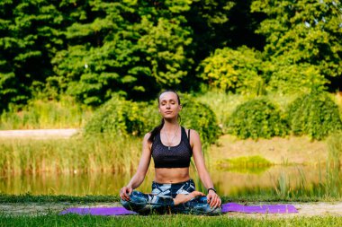 Yeşil park Yoga egzersiz yaparak genç kadın. Tonlu görüntü.