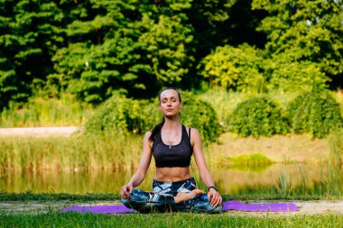 Yeşil park Yoga egzersiz yaparak genç kadın. Tonlu görüntü.