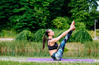 Yeşil park Yoga egzersiz yaparak genç kadın. Tonlu görüntü.