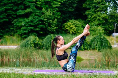 Yeşil park Yoga egzersiz yaparak genç kadın. Tonlu görüntü.