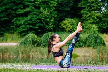 Yeşil park Yoga egzersiz yaparak genç kadın. Tonlu görüntü.