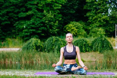 Yeşil park Yoga egzersiz yaparak genç kadın. Tonlu görüntü.