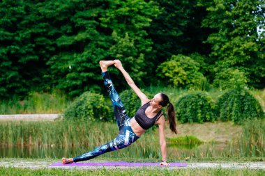 Yeşil park Yoga egzersiz yaparak genç kadın. Tonlu görüntü.