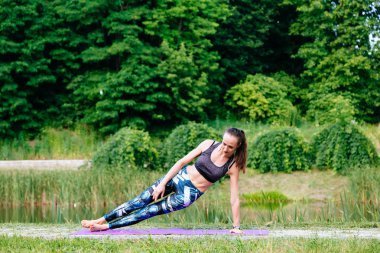 Yeşil park Yoga egzersiz yaparak genç kadın. Tonlu görüntü.