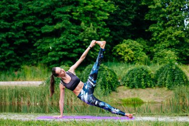 Yeşil park Yoga egzersiz yaparak genç kadın. Tonlu görüntü.