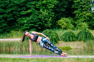 Yeşil park Yoga egzersiz yaparak genç kadın. Tonlu görüntü.