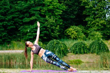 Yeşil park Yoga egzersiz yaparak genç kadın. Tonlu görüntü.