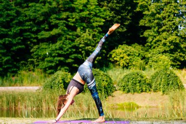 Yeşil park Yoga egzersiz yaparak genç kadın. Tonlu görüntü.