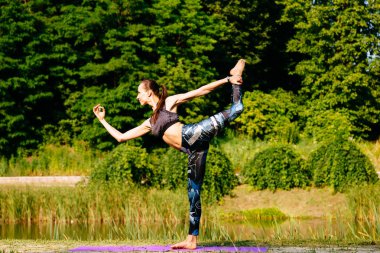 Yeşil park Yoga egzersiz yaparak genç kadın. Tonlu görüntü.