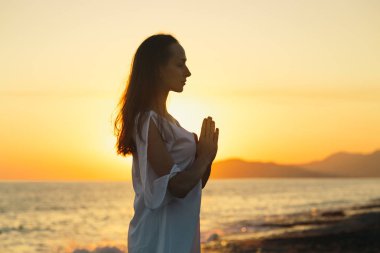 Genç kadın sahilde doğada sabah yoga uygulamak