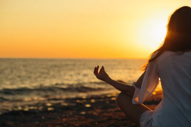 Genç kadın sahilde doğada sabah yoga uygulamak