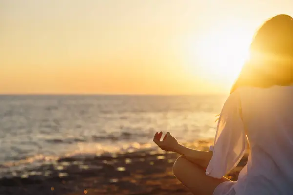 Genç kadın sahilde doğada sabah yoga uygulamak